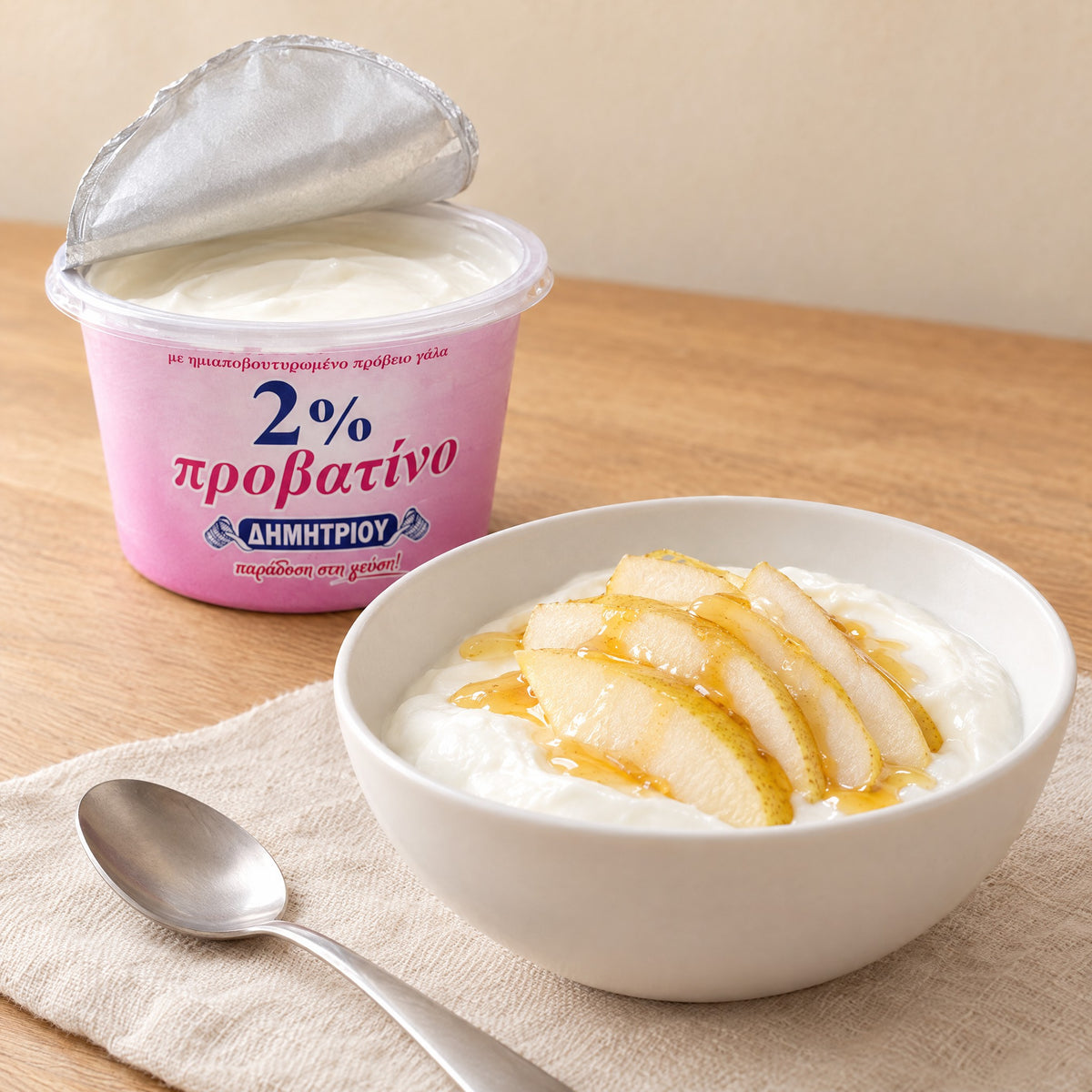 Schale Schafsjoghurt mit Birnenscheiben und Honig neben einem geöffneten Dimitriou-Becher