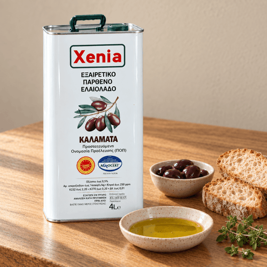 Xenia extra virgin olive oil 4L tin on a wooden table with a bowl of dark olives, rustic bread, a dish of olive oil and fresh oregano