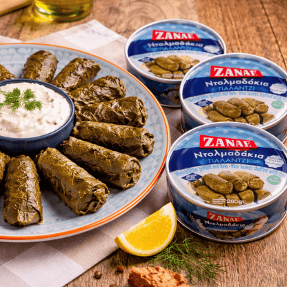 Zanae dolmadakia, vine leaves stuffed with rice and herbs, on a plate beside the round tins