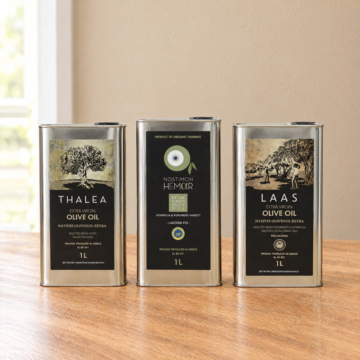 Thalea, Nostimon Hemar and Laas PGI extra virgin olive oil 1L tins by Energaea, side by side on an oak table