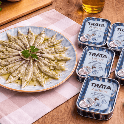 Trata anchovies with oregano on a plate next to their tins