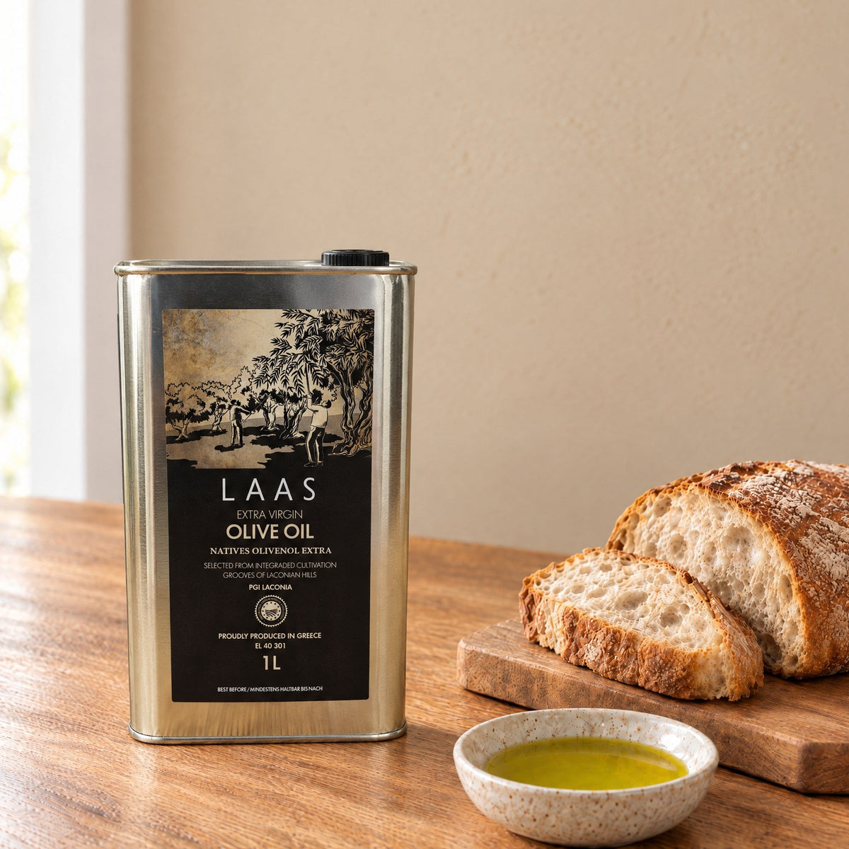 Laas PGI Lakonia extra virgin olive oil 1L tin on a kitchen table with bread and a dish of olive oil