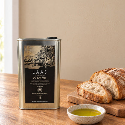 Laas PGI Lakonia extra virgin olive oil 1L tin on a kitchen table with bread and a dish of olive oil