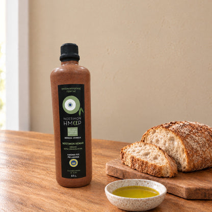 Nostimon Hemar organic Athinolia olive oil in a 500ml ceramic bottle beside bread and a dish of olive oil
