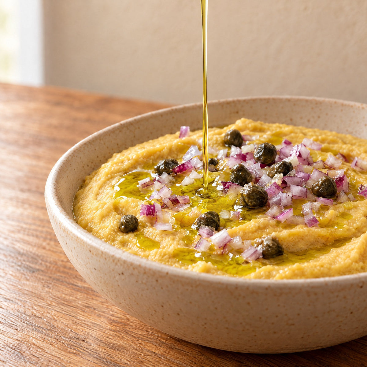 Extra virgin olive oil drizzled over fava split pea purée with red onion and capers