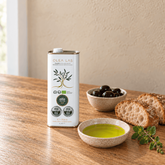 Weiße 1-Liter-Dose Olea Las Olivenöl mit einer Schale schwarzer Oliven, geschnittenem Brot, einer Schale Olivenöl und frischem Oregano