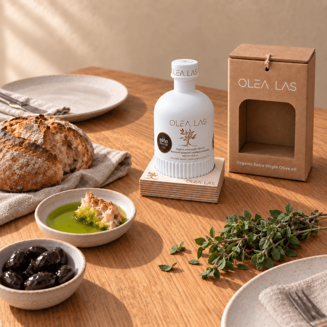 Table set with bread, a dish of olive oil, black olives and fresh oregano next to the 500 ml Olea Las bottle and its gift box