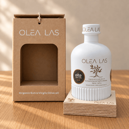 The 500 ml Olea Las bottle on its wooden stand next to the kraft gift box, on an oak table