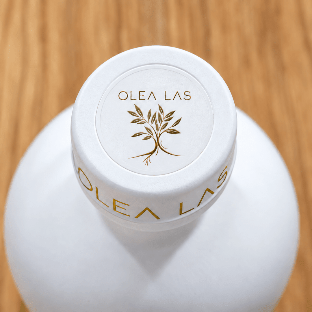 Top view of the white cap of the Olea Las bottle with the gold olive tree emblem