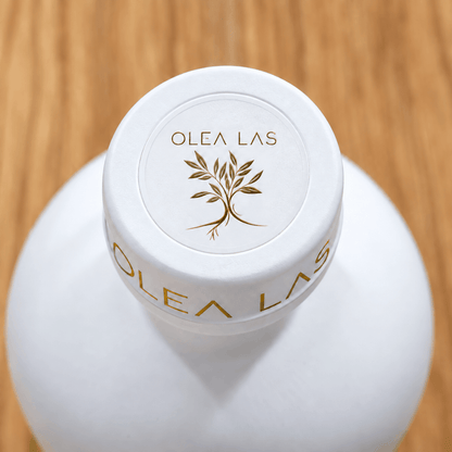 Top view of the white cap of the Olea Las bottle with the gold olive tree emblem