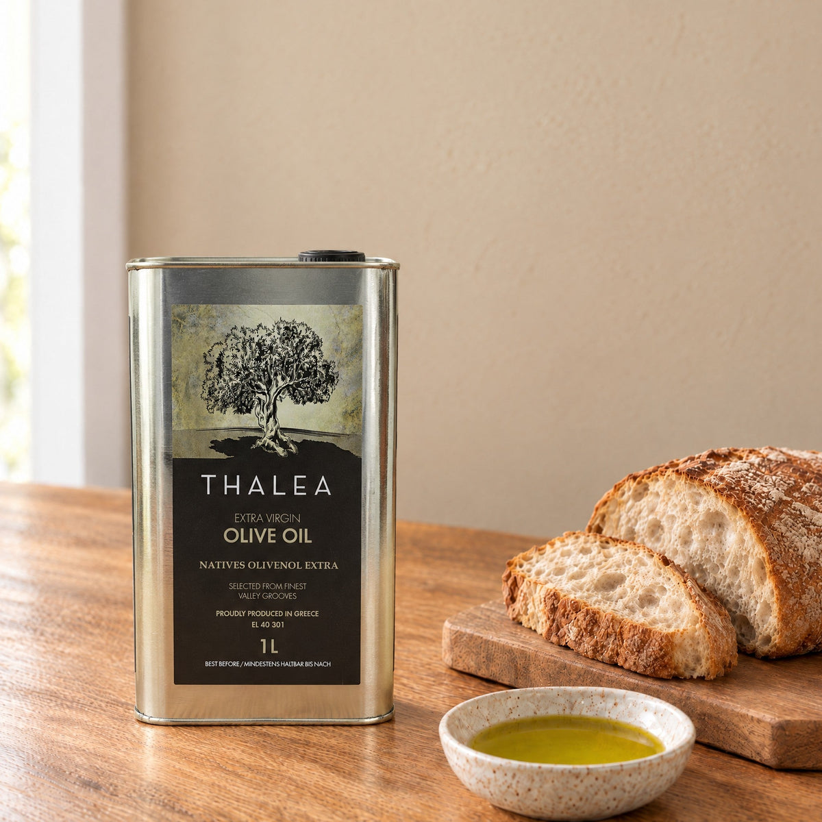 Thalea extra virgin olive oil 1L tin on a kitchen table with bread and a dish of olive oil