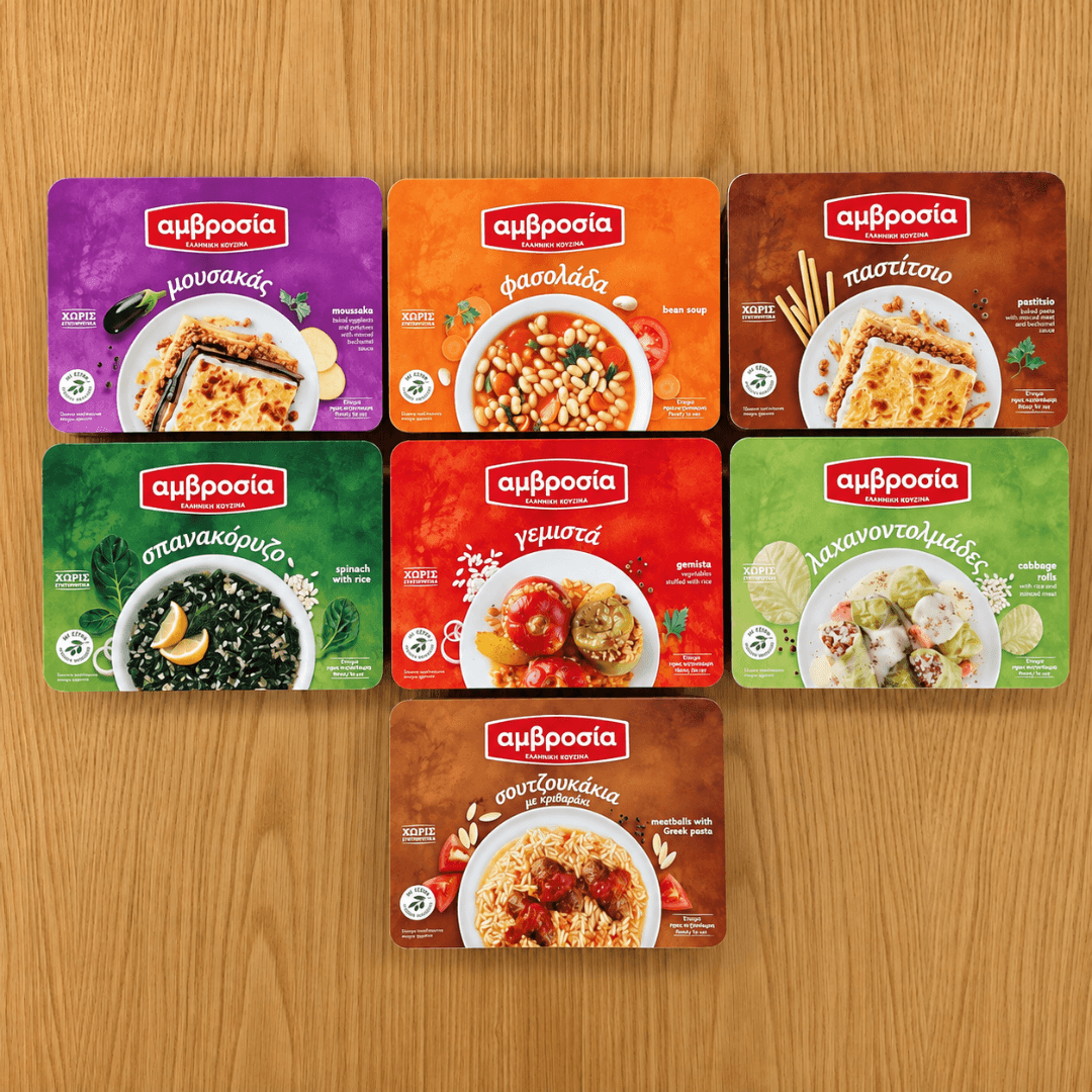 The seven Amvrosia packs seen from above: moussaka, fasolada, pastitsio, spanakorizo, gemista, cabbage rolls and soutzoukakia