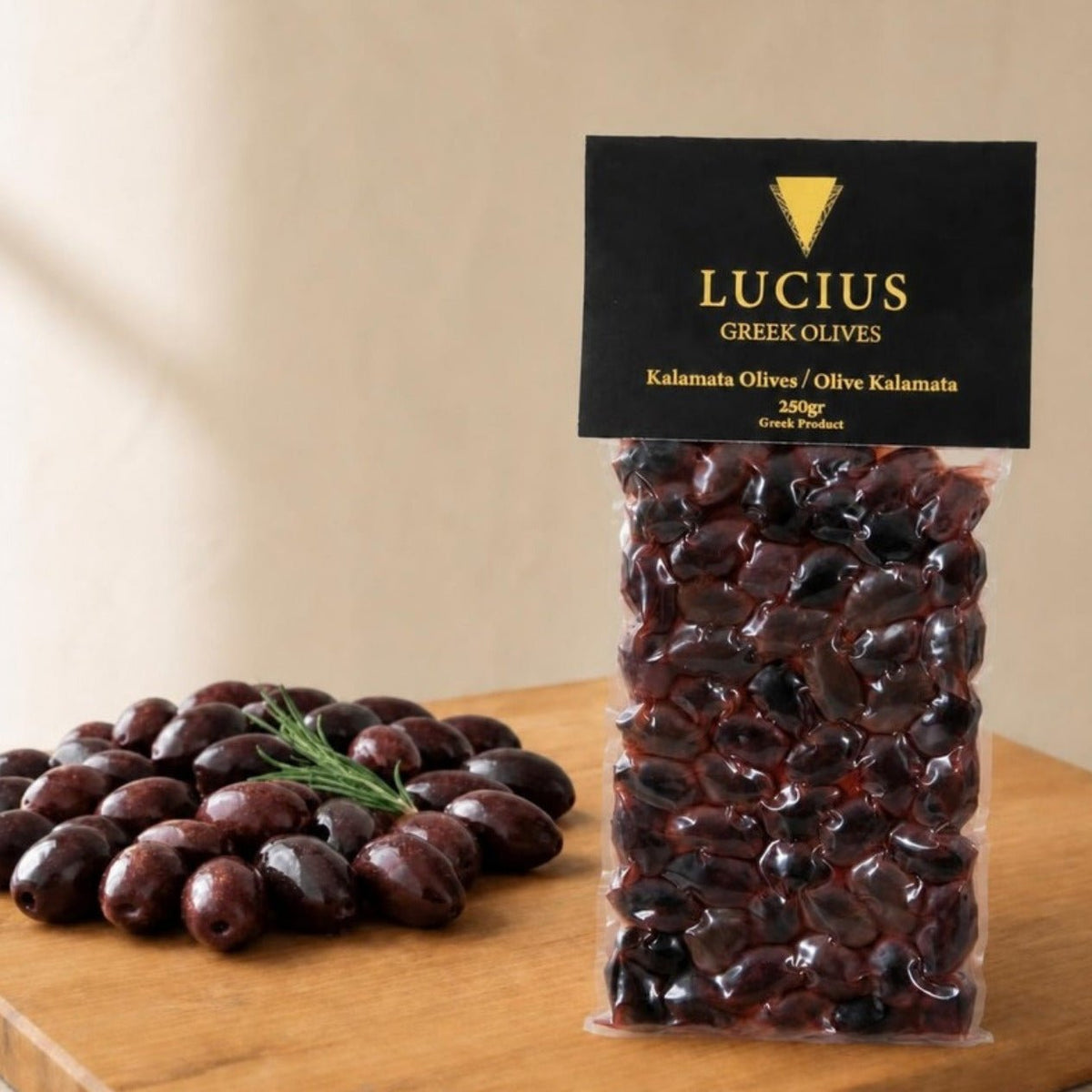 Aceitunas de Kalamata enteras Lucius en bolsa al vacío de 250g junto a un montón de aceitunas sobre una tabla de roble