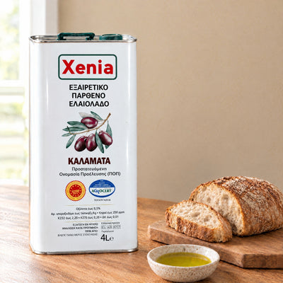 Xenia Kalamata PDO extra virgin olive oil 4L tin on a kitchen table with bread and a dish of olive oil